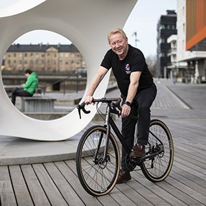 Man på cykel vid sidan om en gråvit modern skulptur